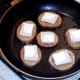 Goats cheese squares are laid on frying potato discs