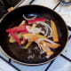 Peppers and onion are flash fried while potatoes drain