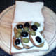 Halved olives are arranged over melted goats cheese and potatoes