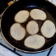 Potato slices are added to hot frying pan seasoned sides down