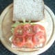 Lettuce on tomato are laid on bread and seasoned
