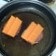 Sliced cheese is laid on folded over bacon