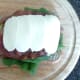 Sliced mozzarella is arranged over bacon