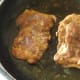 Chicken thighs are turned to fry on second sides