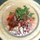 Chickpea salad ingredients are added to mixing bowl