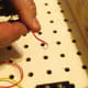 The positive lead from the battery holder is hard-wired to the knife switch to reduce the number of alligator clip connecting wires required. Strip a bit of the plastic coating the wire and make a wire loop.