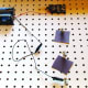 Attach a connecting wire from the negative terminal of the battery to the left side of the third bulb from the switch.