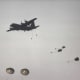 Paratroopers jumping from a C-130 during a mass parachute drop.