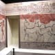 A typical room in the city of Akrotiri with brightly-painted frescoes: two adolescent boys boxing on one wall, a pair of goats dancing in a stylized landscape on the other.