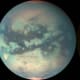 False-color images taken in visible and infrared over the last several years show that Titan changes with the seasons: the poles develop brown caps, and huge dark lakes of methane fill at the tropics from monsoon rains. Light spots may be volcanic.