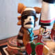 A clown who visits at Harvest, usually seen with watermelon or squash. Notice that the figure is a man with squash blossom whirls at each side of his head, which means he is imitating the traditional hair of a woman.