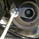 Lodge the pulley holder tool into the crankshaft pulley. Secure the pulley from moving by attaching a long breaker bar to the ground.