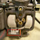 Remove the pin that holds the float in place (circled in red). Remove float and float valve.