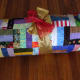 Rolling the quilt and wrapping it with a ribbon will show the fabric, but the quilt pattern will likely still be a mystery.