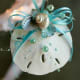 Thread the ribbon of choice through the natural hole of the sand dollar. Glue on tiny abalone, limpet and turban seashells. Thread beads on fishing line and glue.