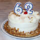 A cake simply decorated with candles, frosting, nuts, and cherries.