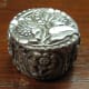 Round fine silver lidded box (approx. 1¼" diameter). Top of lid and four textured appliqués around sides made from my own molds of vintage & antique buttons.
