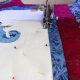 Quilt with a thread color that matches the cross stitch fabric, in the ditch of the inner frame line.