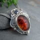 This exquisite backplate echoes the lacy delicacy of this exceptional Russian amber stone accented with a blue sapphire.