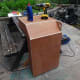 Gluing the centre back panel in place, and giving it added support with a piece of scrap wood fixed to the underside of the top shelf.