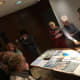 Attendees of the paper cutting workshop at the end of the class admiring each other work. Bonding and networking time.