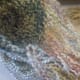 Hooking strands of yarn around base of wig cap.
