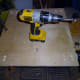 Holes drilled in the base, and through the scrap wood, to fix the wheels