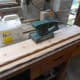 Sanding shelves and hewed edges smooth with an orbital sander.