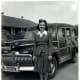 Woman standing in front of 1942 Ford Woodie during World War II.