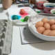 Here, some coloured eggs are drying on a paper towel while some dry eggs have already been placed in the carton.
