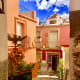 Colorful painted facades in red and pink against the blue sky. There is a picture of a Saint on the wall.