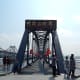 The bridge entrance looks grand, lined each side by patriotic Chinese flags. To the left, you can see the Sino-Korean friendship bridge, which still connects China and North Korea.