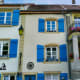 The blue shutters and the vintage ceramic pots on the windowsills add even more charm to the house.