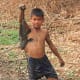 One of the children triumphantly holds up his fish catch for me, after the village fish pool is drained