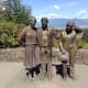 Photo Session is a life-size bronze sculpture of a man photographing three people. Vancouver and a city on the other side of Burrard Inlet are visible in the background.