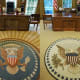New York Magazine referred to the Obama Oval Office rug (right) as the "less-optimistic rug" as compared to the rug from George W. Bush's Oval Office (left) with its radiant lines that move out from the presidential seal.