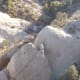 Balanced atop the bottom cliff is a "small" boulder about 8 ft. high.