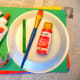 The supplies to make a paper plate apple.