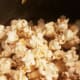 Slowly add popcorn kernels, stirring.