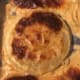 A slice of baked onion covered in cheese and whiskey cream sauce
