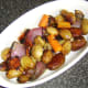 Roast vegetables are laid in the bottom of a serving dish