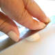 Place garlic clove in skin onto cutting board. With your fingers, press down firmly on the flat side of your knife two or three times. You will hear the skin of the garlic crack.