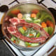 Solid ingredients for beef stock are assembled in stock pot