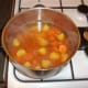 Potatoes, carrots and beef stock are added to pot and seasoned