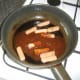 Hoisin and garlic sauce is poured in to pan with cocktail sausages