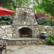 rustic stone outdoor fireplace with raised hearth and round grey and tan stones
