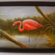 A framed painting of a flamingo in the wetlands.