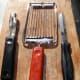 Kitchen Utensils for preparation of the dish including potato peeler, tomato slicer and sharp kitchen knife.