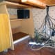 The old Ikea desk relocated to the corner beneath the main desk, and base speaker wired up on the top shelf