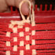 The first step to sealing the edges of a potholder, grab the end of a loop and pull it off the loom making sure to hold on to the loop